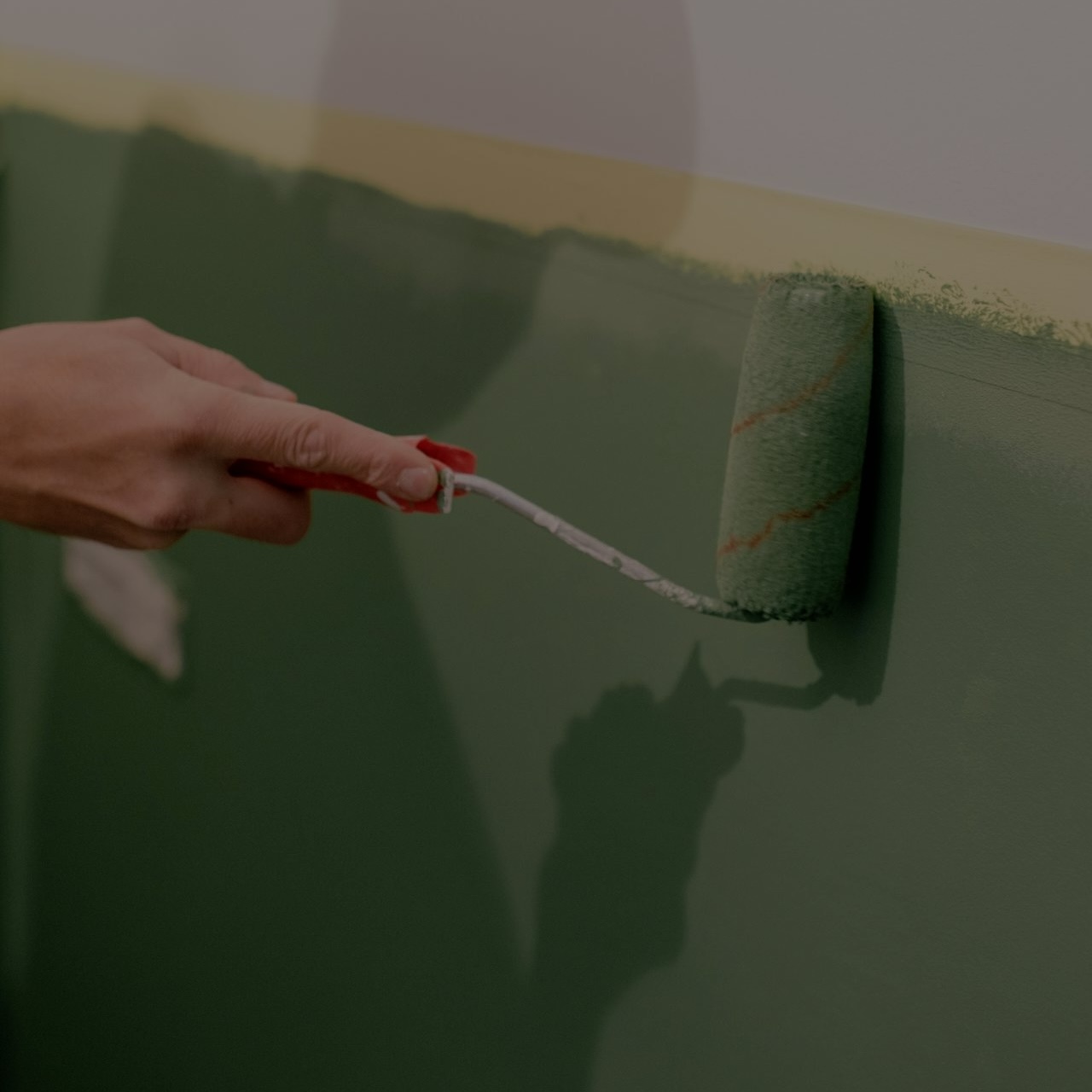 Hånd maler væg med grøn maling